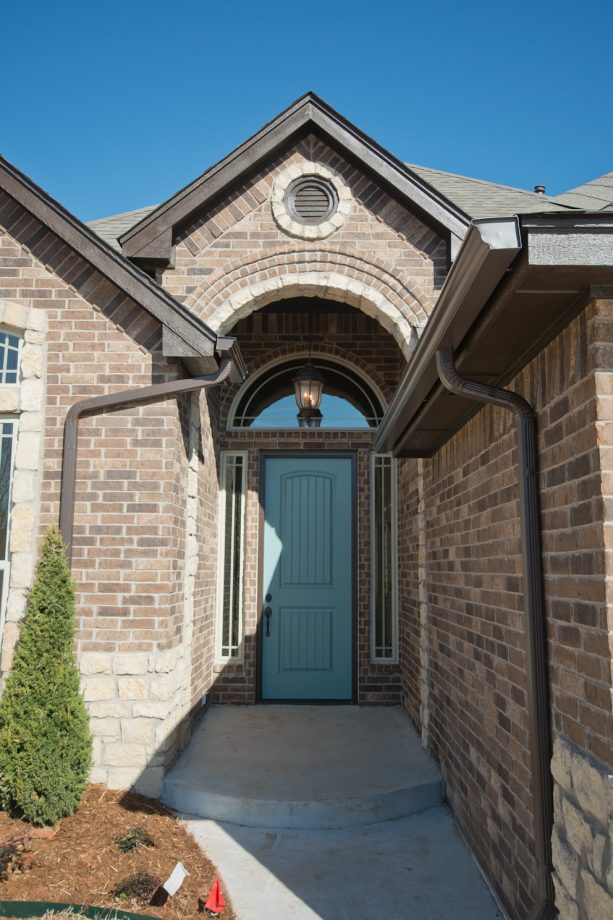 a large brick traditional house completed with a sherwin williams dark moody blue front door