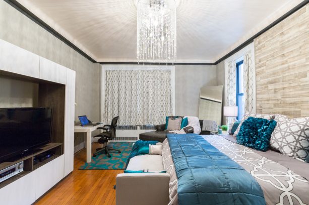 a large modern master bedroom with the ash-gray wall, the combination of fossil and cobalt bed with the teal carpeted on the floor