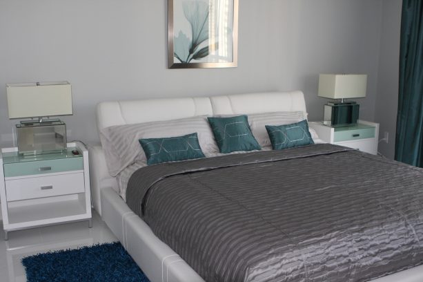 a mid-sized contemporary bedroom with cloud gray wall and teal pillow