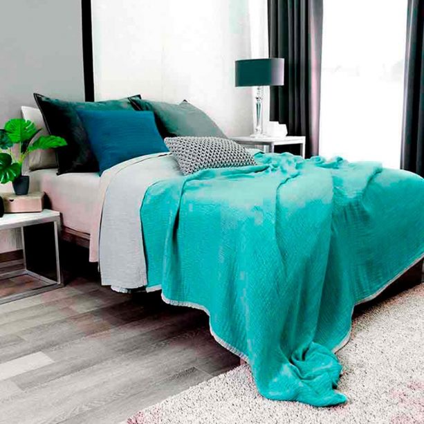 a small trendy master bedroom with gray wall and floor combined with teal bed cover
