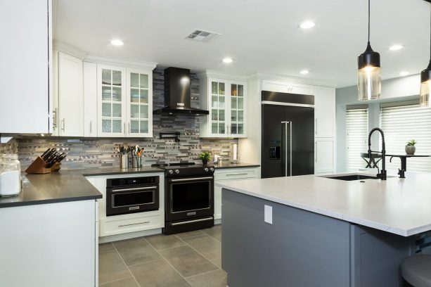 white shaker kitchen cabinet with black appliances and gray backsplash