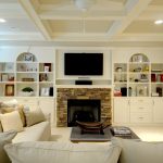 combination of fieldstone fireplace and polished white built-in shelves around