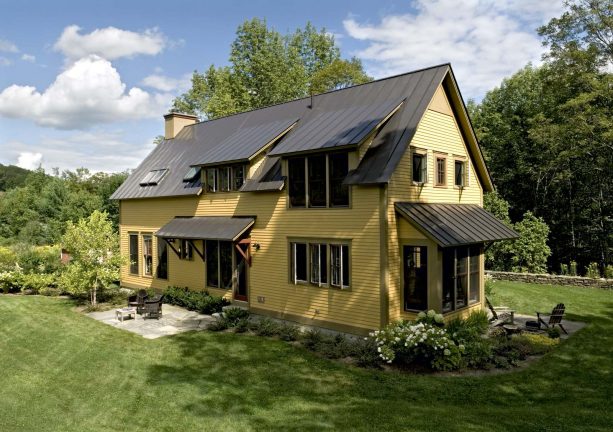 cottage wood exterior with a combination of yellow siding and a bronze metal roof