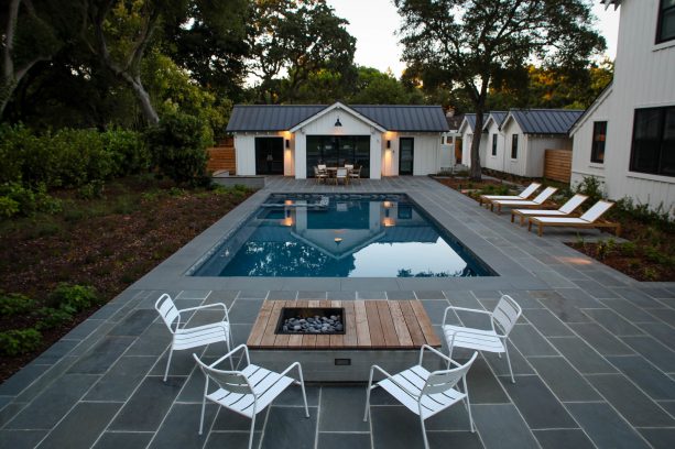 a fire pit seating area and patio with bluestone paver around a pool