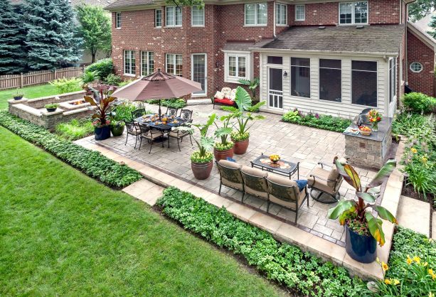 a large classic brick paver patio with dining area and fire pit