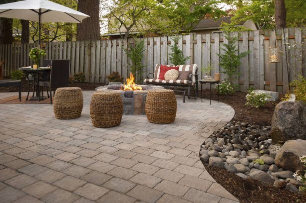 a relaxing patio with a circular stone fire pit and roman cobblestone paver