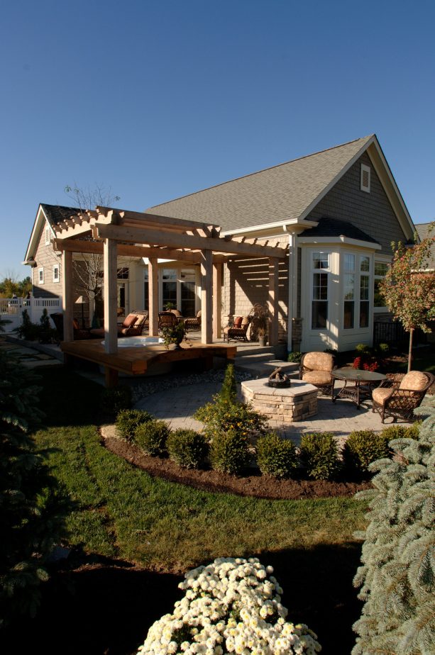 attached pergola on a raised stone patio with a hot tub