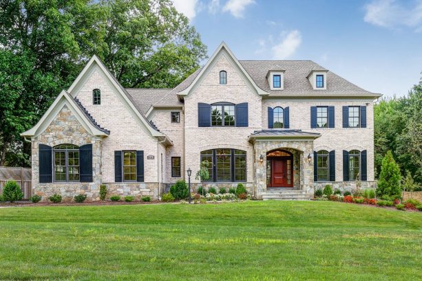 beige three-story brick house featuring glossy shutters