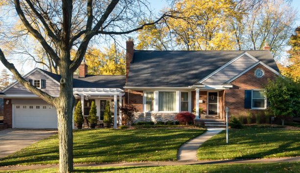 small one-story brick house in grey color with dark green shutters