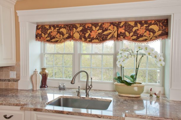 orange colored valance with a pompom as a window treatment over the undermount kitchen sink