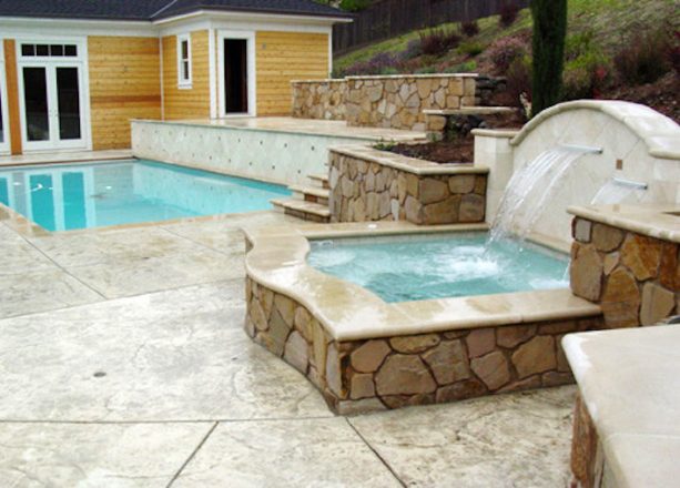 stamped concrete retaining wall for a detached spa and a sloped garden
