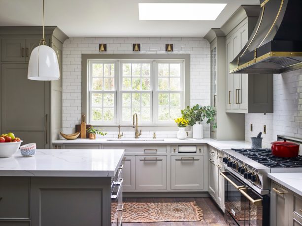 three metallic gold finish wall-mounted sconce lights over a double-bowl sink