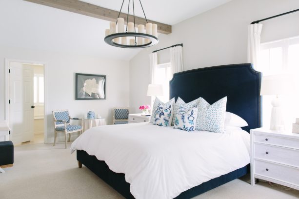 navy bed with tall headboard in a polished white bedroom