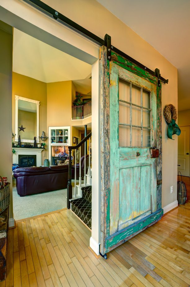 a single barn door in teal color and worn-out look with windows