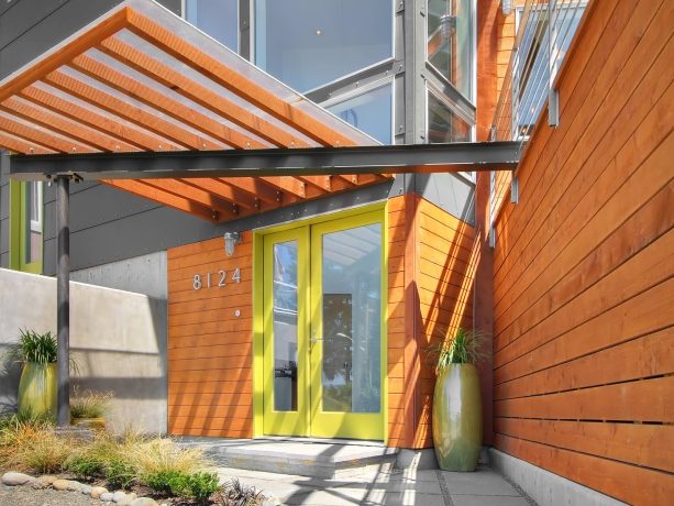 glass front door with a yellow frame surrounded by cedar siding