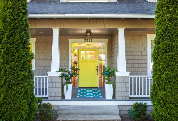 semi-gloss yellow painted front door framed by a glass panel