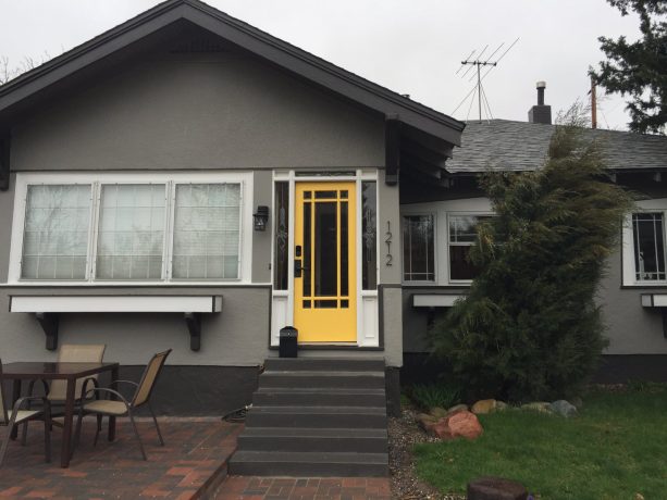 yellow front door around gray stucco wall