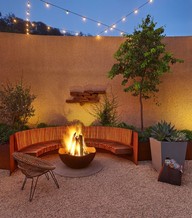 small pea gravel fire pit area with a half circular wooden bench