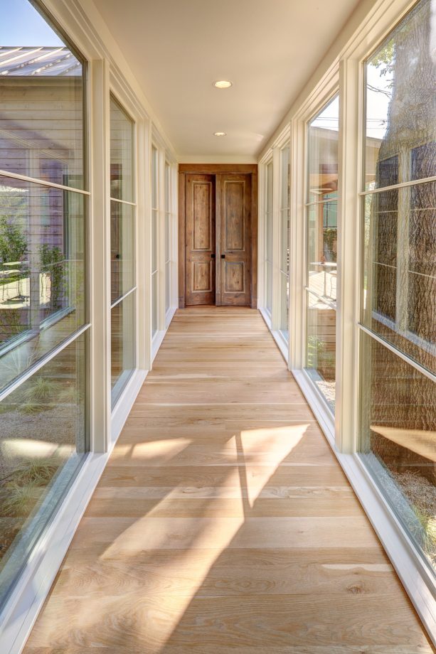 the idea for a transitional hallway with a medium tone wood door and a light wood floor