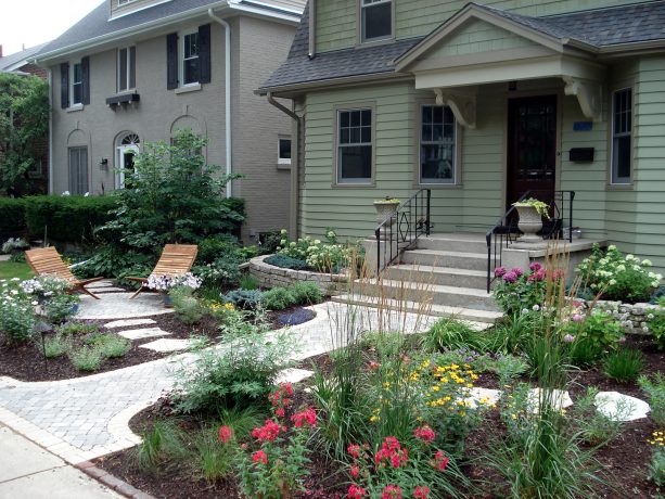 colorful perennials and shrubs with paver path and stone walkway in a grassless front yard