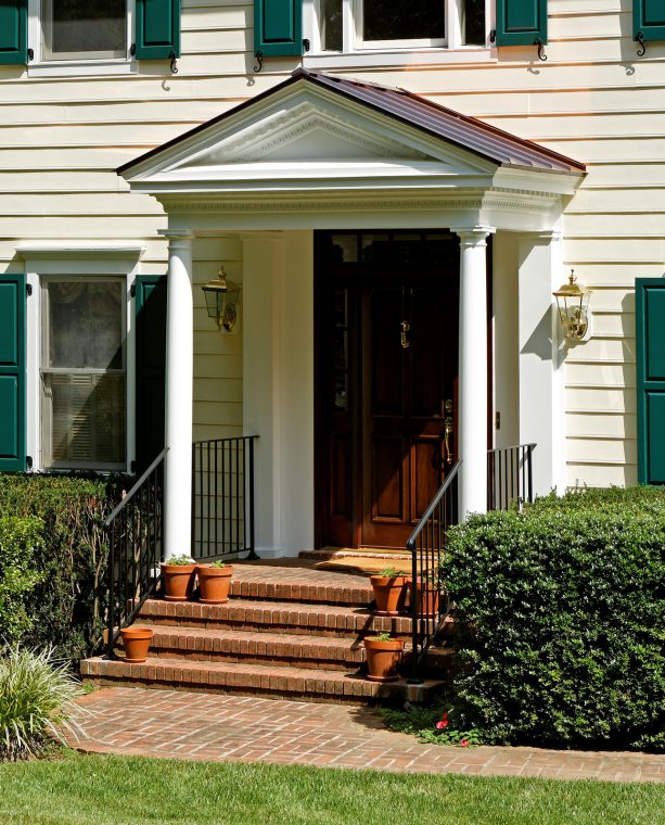 elevated entrance with a classic front door portico made of standing seam copper roof and white pillars