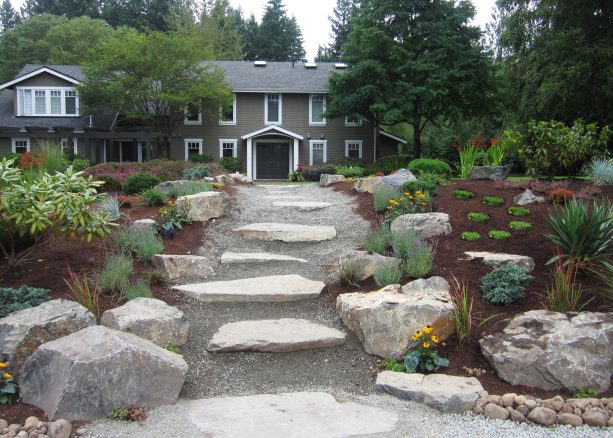 rock and boulder path in the middle of the soil-plant bed in a grassless front yard