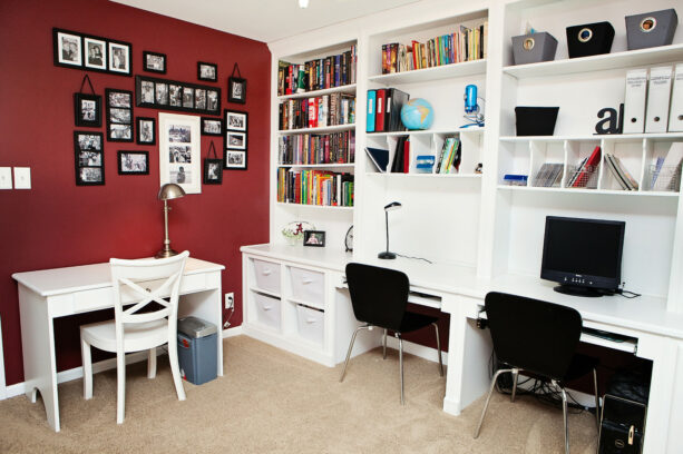 dark red painted office accent wall with black and white framed pictures