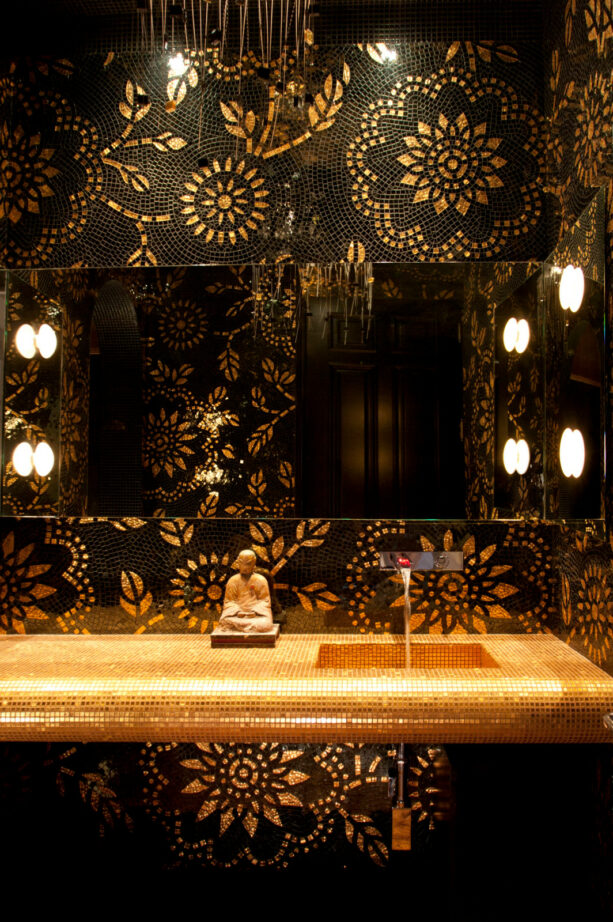 glass mosaic in black with gold accent on a wall of a powder room