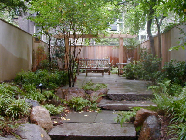 raised bluestone patio with a pergola in a townhouse backyard