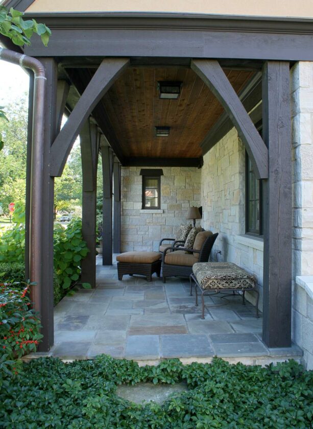 stone front porch with chairs, ottoman, and cushioned bench as seating