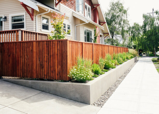 a combination of cedar and steel fence with bushes in a front yard to boost privacy