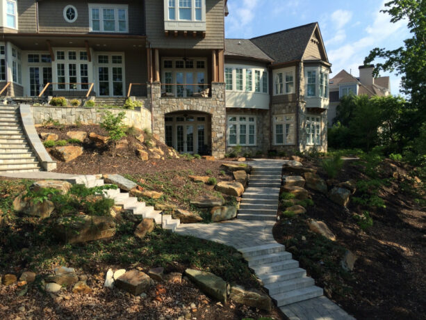 concrete slab steps are accentuated by large boulders in low-maintenance hillside landscaping