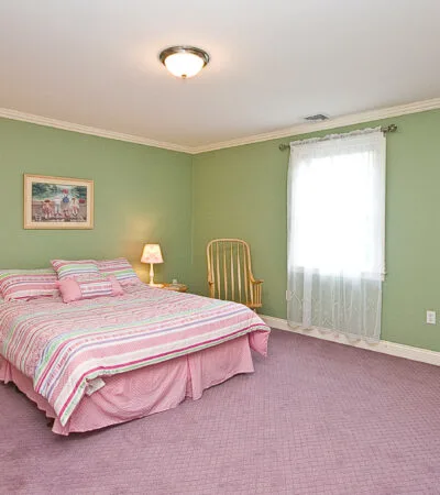 pale mint green wall with pink duvet and carpet in a traditional bedroom