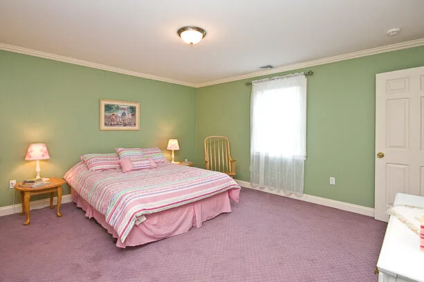 pale mint green wall with pink duvet and carpet in a traditional bedroom